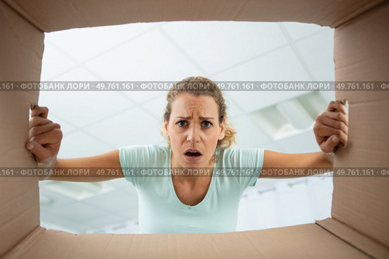 low angle view of disgruntled woman looking into cardboard box. Стоковое фото, агентство Ingram Publishing / Фотобанк Лори