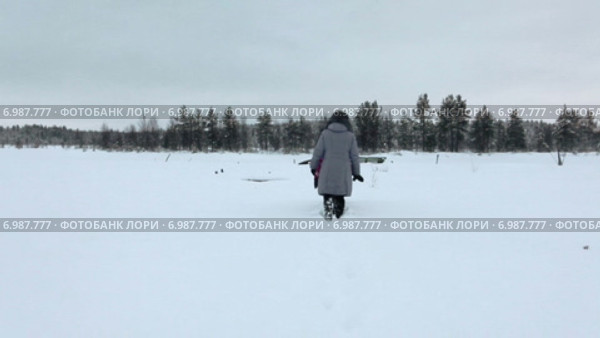 Люди пробираются сквозь сугробы по заснеженной тропинке на болоте к лесу. Карелия. Стоковое видео, видеограф Кекяляйнен Андрей / Фотобанк Лори