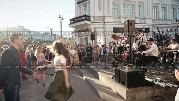 Люди слушают музыку, веселятся и танцуют на городской улице под духовой оркестр. People listen to music, have fun and dance in the city street to the music of a brass band. Omsk, Russia (2019 год). Редакционное видео, видеограф EStarodubov / Фотобанк Лори