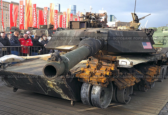 Люди смотрят на дуло вниз у американского танк Abrams М1А1. Выставка трофейного вооружения и военной техники, захваченной российскими военными в ходе спецоперации. Парк Победы на Поклонной горе, Москва (2024 год). Редакционное фото, фотограф SevenOne / Фотобанк Лори