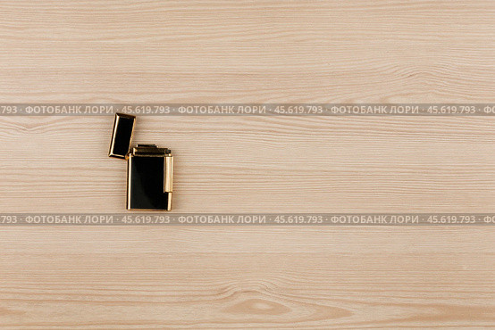 Luxury gold lighter lying on a wooden surface. With room for your text. Стоковое фото, фотограф Александр Собко / Фотобанк Лори