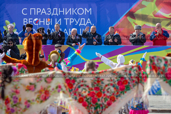 Magadan, Magadan Region, Russia - May 1, 2018. Festive May Day concert on the city square. The government of the Magadan region is on the podium. Text in Russian: Happy Spring and Labor Day! Редакционное фото, фотограф Андрей Степанов / Фотобанк Лори