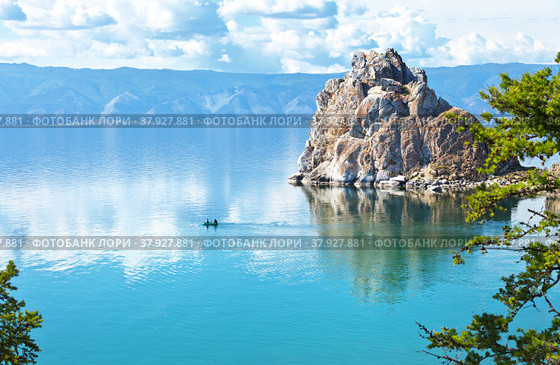 Magnificent summer landscape with Baikal Lake on a sunny day. Tourists travel in a rubber boat around the famous Shaman Rock. Flocks of June midges are visible on water. Natural background. Стоковое фото, фотограф Виктория Катьянова / Фотобанк Лори