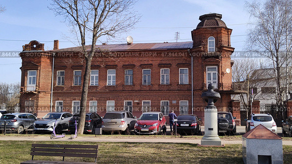 Main house of estate of merchant Zotov. Old brick building with annex on Dzerzhinsky Street, 11. Cars parked at historic city building. Kostroma, Russia, April 17, 2025. Редакционное фото, фотограф Ирина / Фотобанк Лори