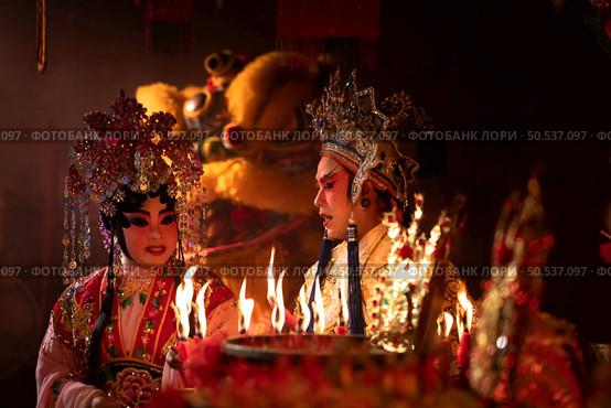 Male and female Chinese opera actors Light a candle to pray homage to the gods to enhance the prosperity for yourself on the occasion of the Chinese New Year festival. Стоковое фото, агентство Ingram Publishing / Фотобанк Лори