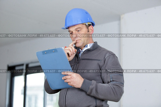 male architect holding clipboard indoors. Стоковое фото, агентство Ingram Publishing / Фотобанк Лори