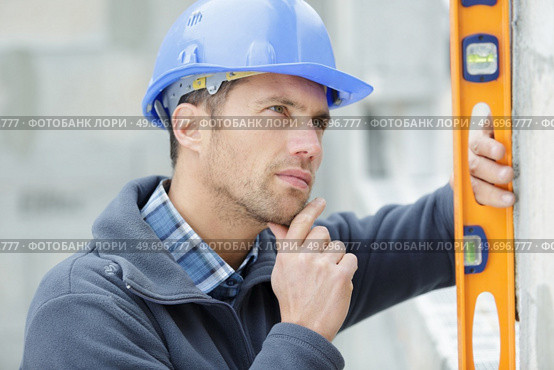 male builder thinking about level wall. Стоковое фото, агентство Ingram Publishing / Фотобанк Лори