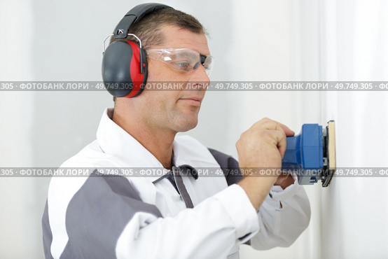 male builder using sander on plasterboard wall. Стоковое фото, агентство Ingram Publishing / Фотобанк Лори