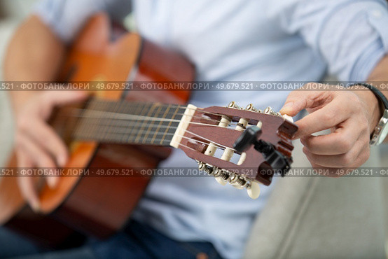 male hands tune acoustic guitar. Стоковое фото, агентство Ingram Publishing / Фотобанк Лори