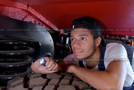 male mechanic using a torch to light up the engine. Стоковое фото, агентство Ingram Publishing / Фотобанк Лори