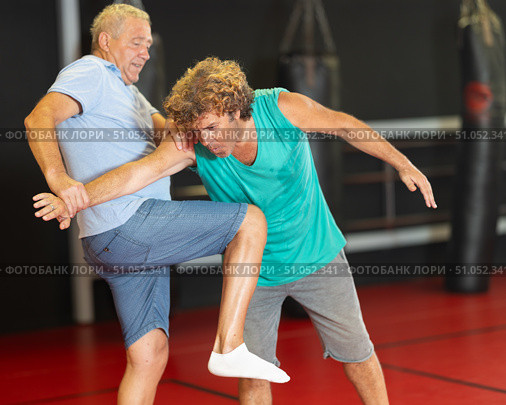 Male pupil clash with training manager during self-defense lesson, repulse charge, intensity of practice. Стоковое фото, фотограф Яков Филимонов / Фотобанк Лори