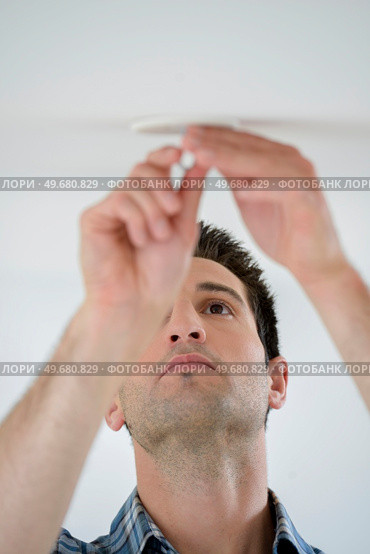 male worker replacing a broken bulb. Стоковое фото, агентство Ingram Publishing / Фотобанк Лори