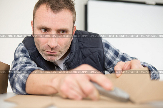 male worker scoring cardboard with craft knife. Стоковое фото, агентство Ingram Publishing / Фотобанк Лори