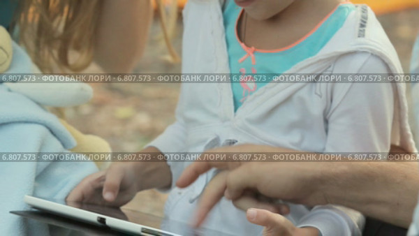 Маленькая блондинка с семьей на природе играет на планшете. Стоковое видео, видеограф Denis Mishchenko / Фотобанк Лори