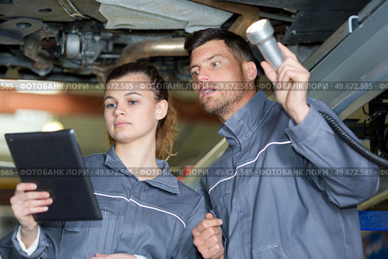 man and woman mechanic examine the underside of a car. Стоковое фото, агентство Ingram Publishing / Фотобанк Лори