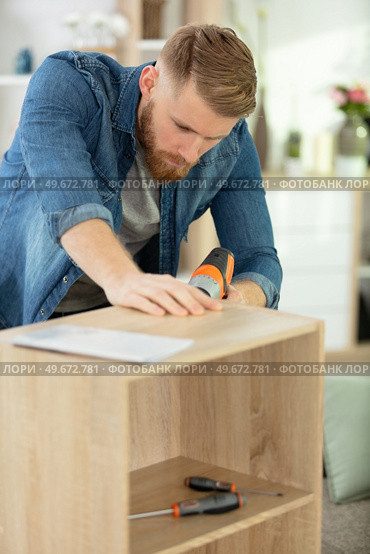 man assembles furniture in the home. Стоковое фото, агентство Ingram Publishing / Фотобанк Лори