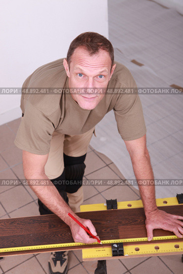 Man at home cutting wooden flooring to size. Стоковое фото, агентство Ingram Publishing / Фотобанк Лори