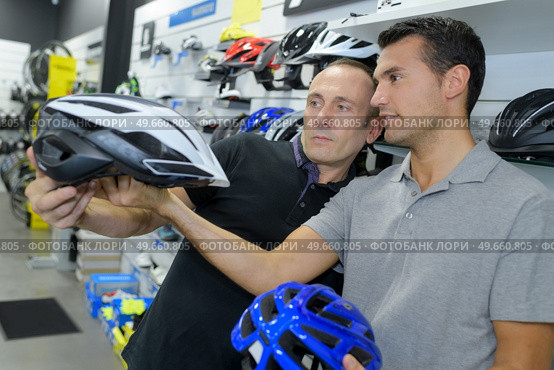 man chooses helmet for cycling before buying in sports shop. Стоковое фото, агентство Ingram Publishing / Фотобанк Лори