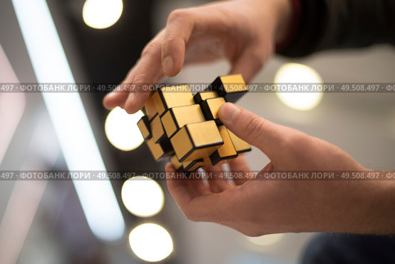 man collects the cube rubik. Intellectual puzzle. Редакционное фото, агентство Ingram Publishing / Фотобанк Лори
