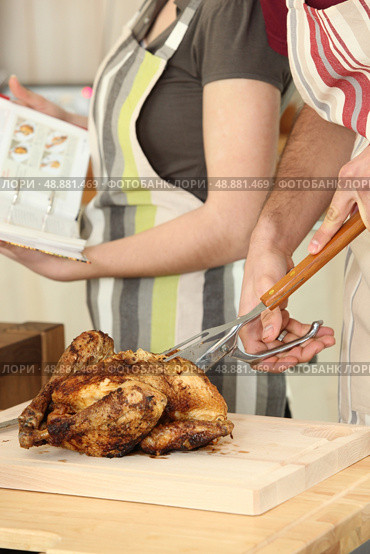 Man cutting chicken on a cutting board. Стоковое фото, агентство Ingram Publishing / Фотобанк Лори