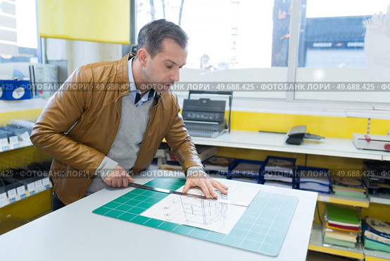 man cutting paper manually. Стоковое фото, агентство Ingram Publishing / Фотобанк Лори