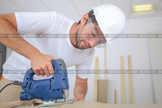 man cutting wood block with fretsaw at the workshop. Стоковое фото, агентство Ingram Publishing / Фотобанк Лори