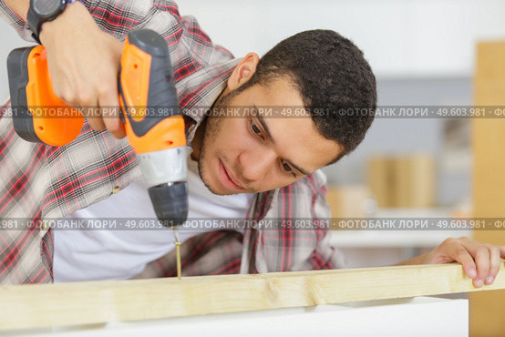 man drilling wood with cordless drill on the table. Стоковое фото, агентство Ingram Publishing / Фотобанк Лори