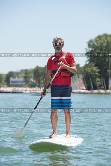 man enjoying a ride on the lake with paddleboard. Стоковое фото, агентство Ingram Publishing / Фотобанк Лори