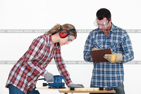 Man evaluating a tradeswoman on her use of a jigsaw. Стоковое фото, агентство Ingram Publishing / Фотобанк Лори