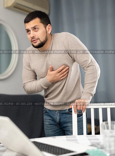 Man experiencing chest pain after working long hours on laptop. Стоковое фото, фотограф Яков Филимонов / Фотобанк Лори