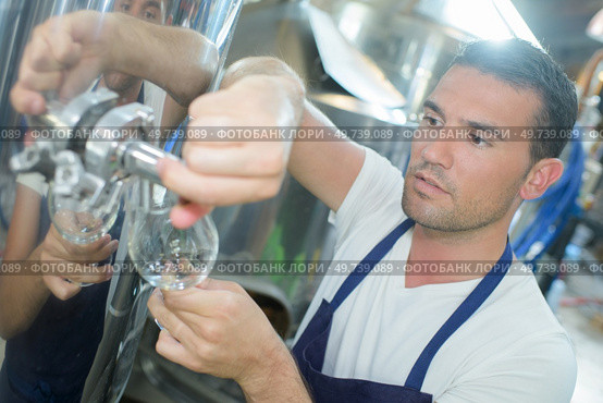 Man filling glass from industrial vat. Стоковое фото, агентство Ingram Publishing / Фотобанк Лори