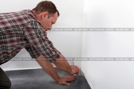 Man fitting linoleum flooring into the corner of a room. Стоковое фото, агентство Ingram Publishing / Фотобанк Лори