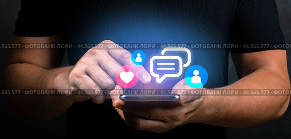 Man hand holding phone with virtual icons interface. male hands hold cell phone with holograms of icons social networks and applications, hearts, likes, messages. digital world online concept. Стоковое фото, фотограф Павел Муравьев / Фотобанк Лори