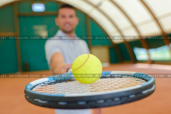 Man holding forward a tennis ball on a racket. Стоковое фото, агентство Ingram Publishing / Фотобанк Лори