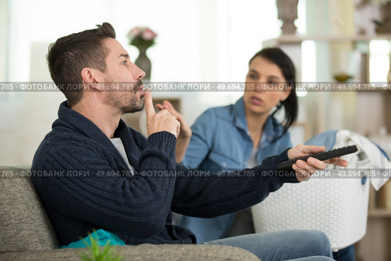 man hushing wife while watching television. Стоковое фото, агентство Ingram Publishing / Фотобанк Лори
