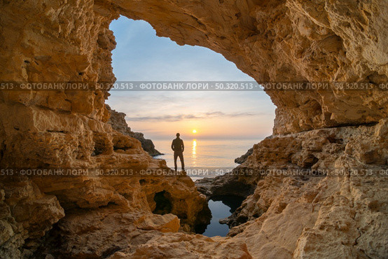 Man in sea grotto. Sea cave mainsail nature landsacpe. . Стоковое фото, агентство Ingram Publishing / Фотобанк Лори