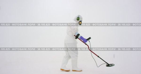 Man in white chemical protection suit holds metal detector. Стоковое видео, видеограф Aleksey Kidisyuk / Фотобанк Лори