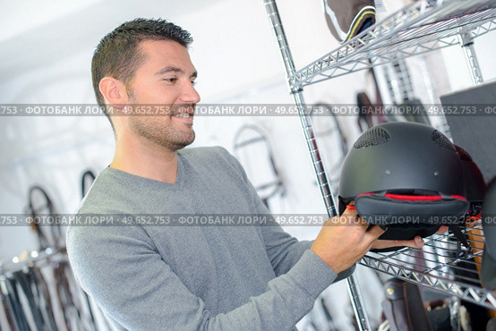 Man looking at horse riding helmet. Стоковое фото, агентство Ingram Publishing / Фотобанк Лори