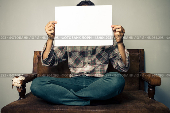 man on sofa holding a sign. Стоковое фото, агентство Ingram Publishing / Фотобанк Лори