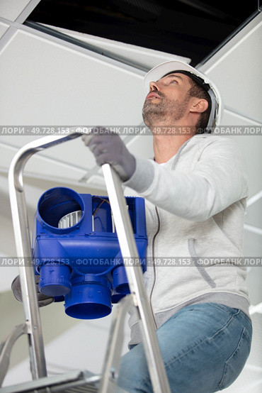 man on stepladder installing a ventilation system. Стоковое фото, агентство Ingram Publishing / Фотобанк Лори