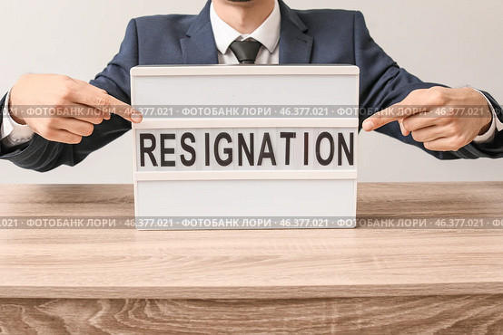 Man pointing at board with text RESIGNATION at table. Стоковое фото, фотограф Pixel_shot / Фотобанк Лори