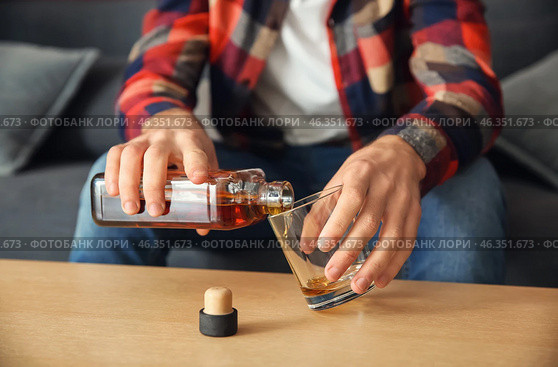 Man pouring alcohol from bottle into glass at table, closeup. Alcoholism concept. Стоковое фото, фотограф Pixel_shot / Фотобанк Лори