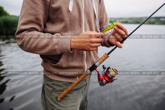 man s hand holding fishing lure rod. Стоковое фото, агентство Ingram Publishing / Фотобанк Лори