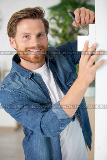 man screwing a device on the wall. Стоковое фото, агентство Ingram Publishing / Фотобанк Лори