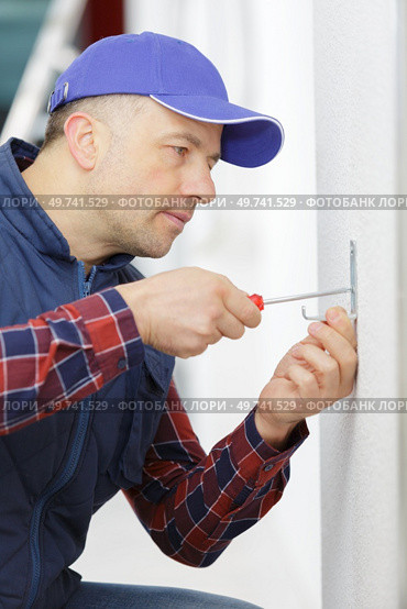 man screwing a hook on the wall. Стоковое фото, агентство Ingram Publishing / Фотобанк Лори