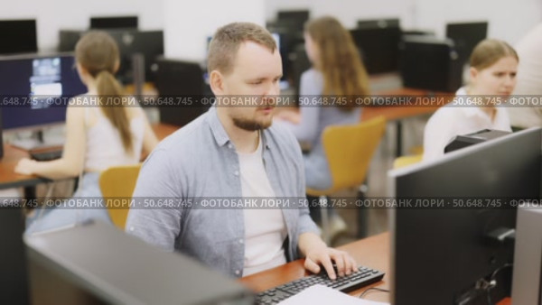 Man student of computer courses looks at monitor screen, types on keyboard and does work. Стоковое видео, видеограф Яков Филимонов / Фотобанк Лори