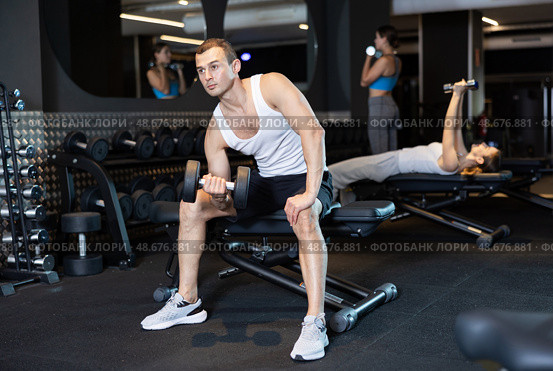 Man trains muscles of arms and back using dumb-bell shaped figure weighting. Стоковое фото, фотограф Яков Филимонов / Фотобанк Лори