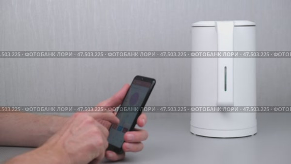Man turns on kettle using an application on his smartphone. internet of things - home wi-fi management, devices and appliances with mobile phone. smart home. Стоковое видео, видеограф ЛУНИНА ВЕРОНИКА / Фотобанк Лори