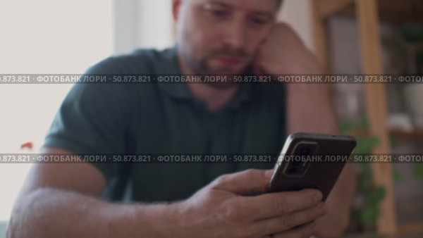 Man using his cellphone. Handsome guy use mobile phone at home. Male browses social networks, gaming, does shopping online, chats with friends, writes or reads messages. Close up. 4k video footage. Стоковое видео, видеограф Марина Демидюк / Фотобанк Лори