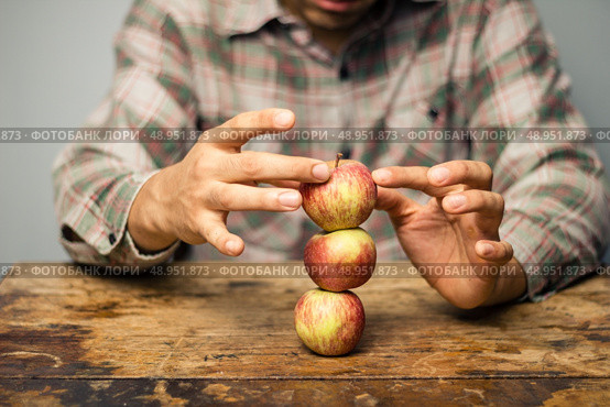 Man with apples balancing on a desk. Стоковое фото, агентство Ingram Publishing / Фотобанк Лори